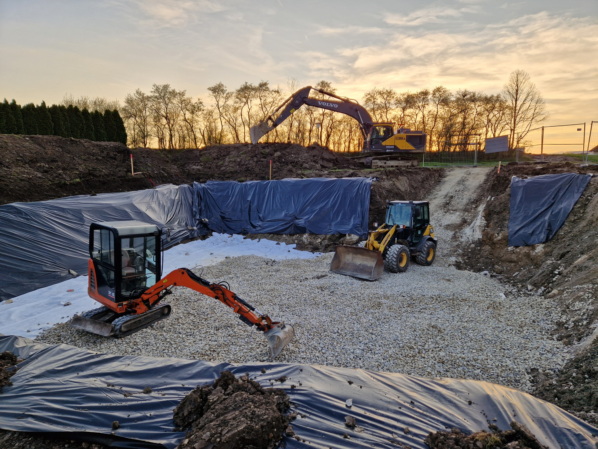 Tiefbau-Baustelle mit Baggern und Radlader bei Sonnenuntergang